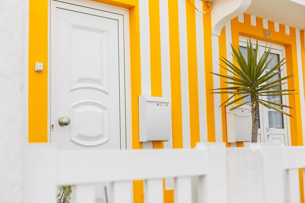 Beautiful colored yellow striped house with doors a bell a white letter mail box and a palm tree Colorful Bright resort cottage with terrace