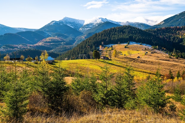 Beautiful colorful forests covering the Carpathian mountains and a small village against the background of a warm autumn sky