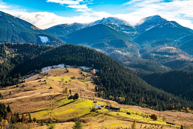 Beautiful colorful forests covering the Carpathian mountains and a small village against the background of a warm autumn sky