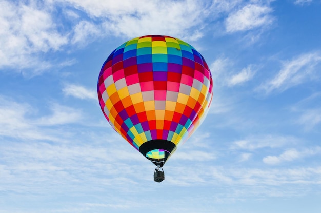 Bella colorata mongolfiera che sorvola un cielo blu con nuvole bianche, sport e avventure