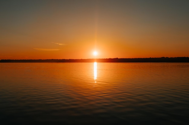 湖の美しいカラフルなオレンジ色の夕日明るい太陽と水の自然の風景の反射