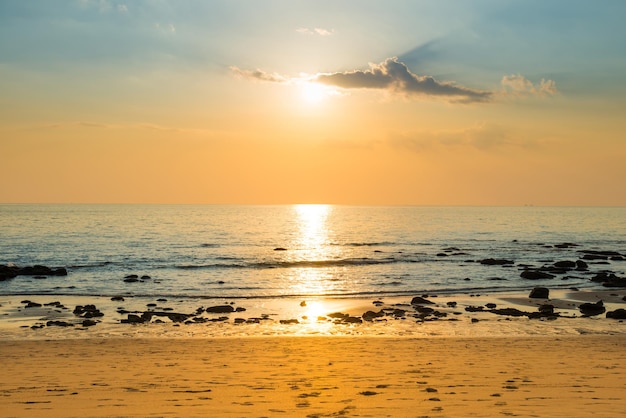 Beautiful colorful sunset landscape with sand beach, golden sun and stones at sea shore