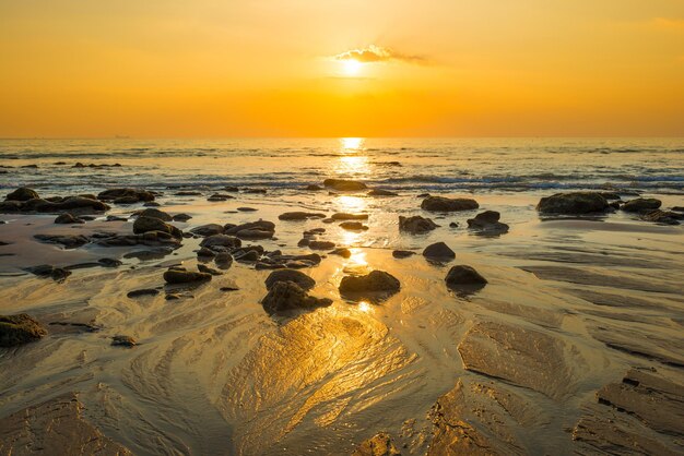 砂浜、黄金の太陽、海岸の石と美しいカラフルな夕日の風景