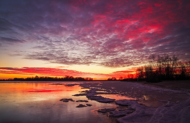 Beautiful colorful winter landscape with frozen lake and sunset sky. Unusual weather phenomenon