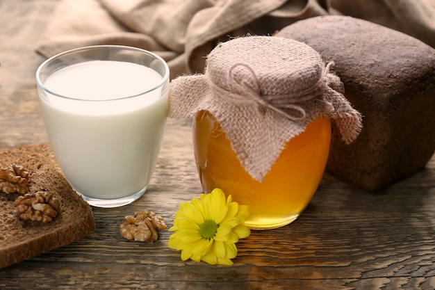 Beautiful composition of golden honey and milk on wooden table