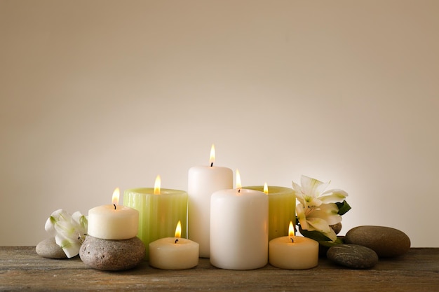 Beautiful composition with candles and spa stones on light background