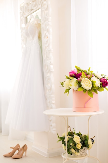 Beautiful composition with colorful peonies in a round box, high heels and wedding dress