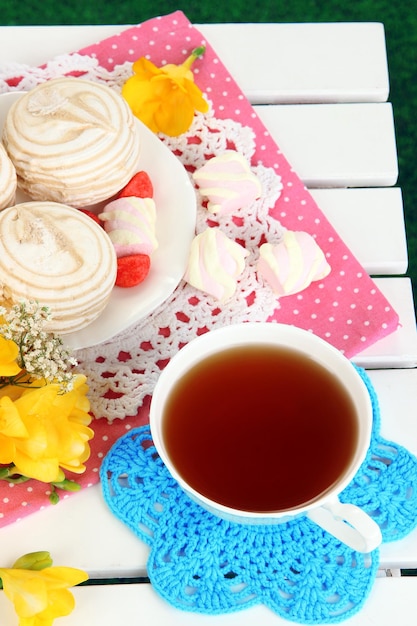 Photo beautiful composition with cup of tea and marshmallow on wooden picnic table closeup