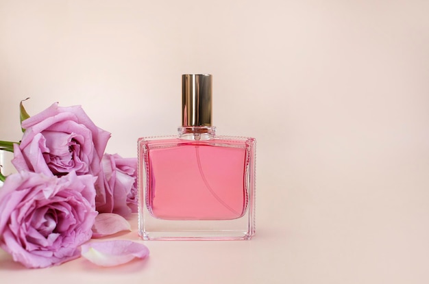 Bella composizione con profumo e fiori bottiglie di profumo petali di fiori di rosa foglie verdi su sfondo rosa vista dall'alto spazio copia piatta profumeria cosmetici collezione di fragranze d'acqua da toilette