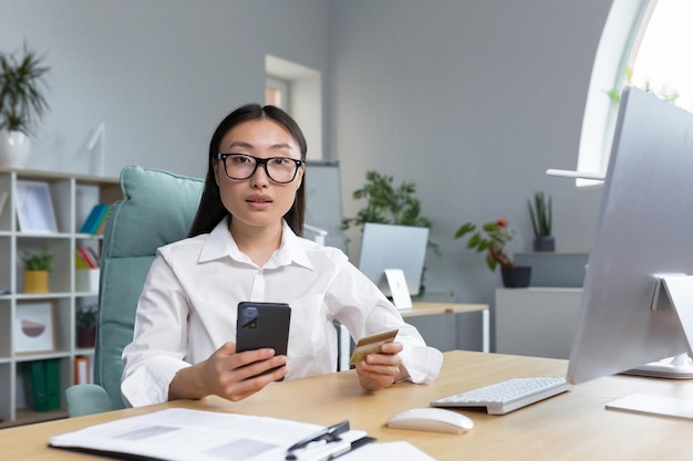 Beautiful and confident asian business woman working in the office making banking transactions using