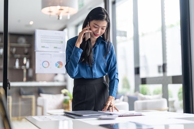 Beautiful confident asian secretary woman clever smart professional business woman talking on phone in office