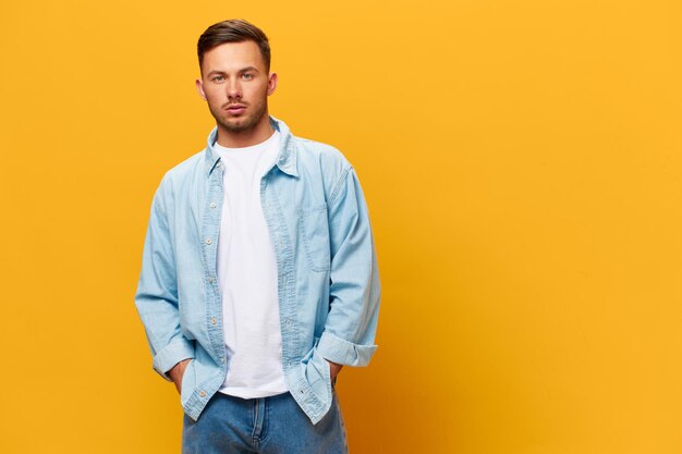 Beautiful confident serious tanned handsome man in blue basic\
tshirt look at camera posing isolated on orange yellow studio\
background copy space banner mockup people emotions lifestyle\
concept