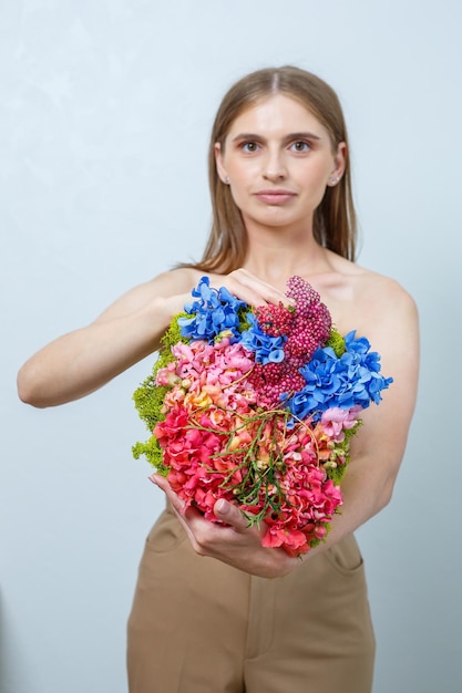 Beautiful confident woman holding fresh spring flowers in her hands Fresh flowers in the hands of a fairhaired woman