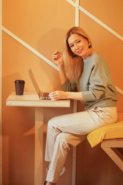 Красивая уверенная в себе женщина, сидящая в кафе, работает фотография образа жизни