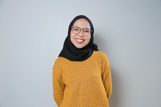 Beautiful and confident young asian muslim woman wearing orange sweater and glasses