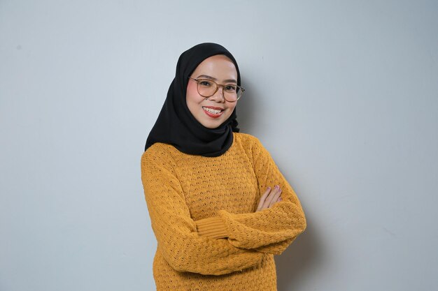 Beautiful and confident young asian muslim woman wearing orange sweater and glasses