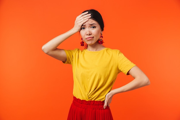 beautiful confused displeased young woman posing isolated over orange wall.