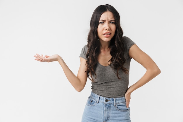 a beautiful confused displeased young woman posing isolated over white wall.