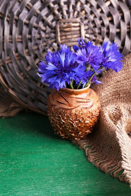 Beautiful cornflowers in vase on wooden background