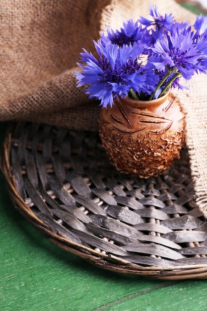 Beautiful cornflowers in vase on wooden background