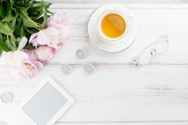 Beautiful cosmetics and flowers flat lay with note book, herbal tea on pastel background.