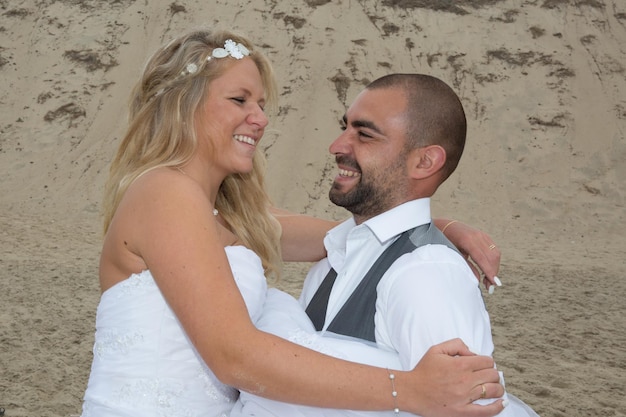 Foto bella coppia sulla spiaggia in abito da sposa