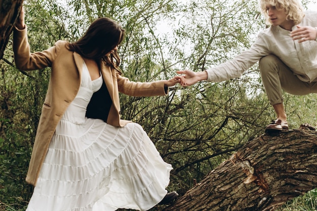 Photo a beautiful couple in the boo style embraces sitting on a branch over the lake