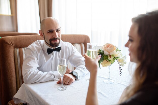 レストランでシャンパンを祝って、飲む美しいカップル。