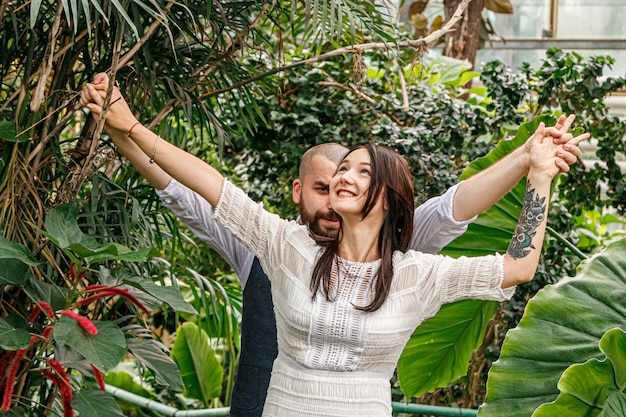 Beautiful couple girl and guy in the park among tropical trees