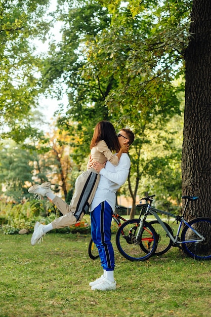 자전거와 나무를 배경으로 공원에서 키스하는 아름다운 커플
