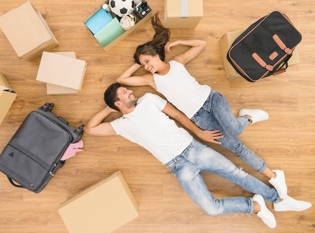 The beautiful couple lay on the floor near boxes. view from above