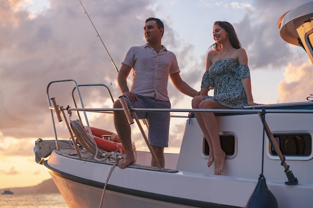 Beautiful couple looking at sunset from the yacht