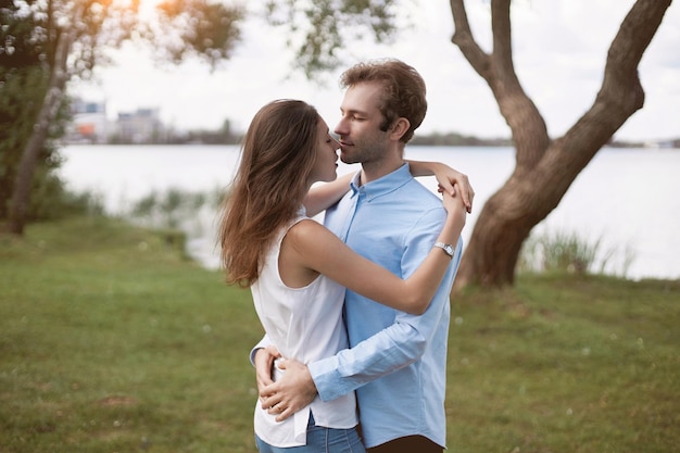 Beautiful couple in love hugs standing on the river bank