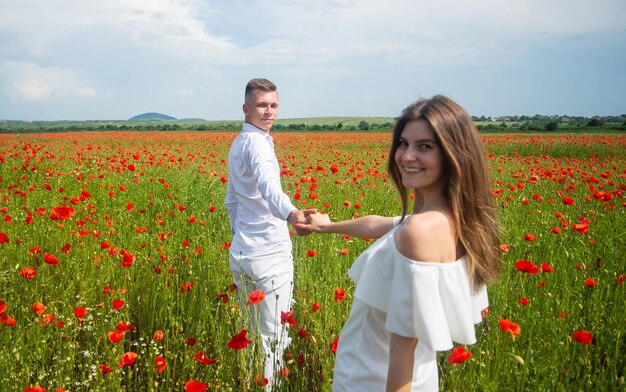 Beautiful couple in love man and woman in poppy flower field summer vacation happy family among red flowers spring nature beauty love and romance romantic relationship