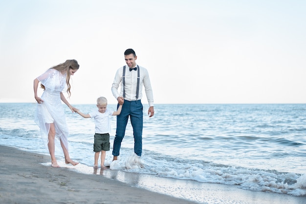 Belle coppie nell'amore che cammina sull'oceano. giovane famiglia con bambino che cammina in riva al mare