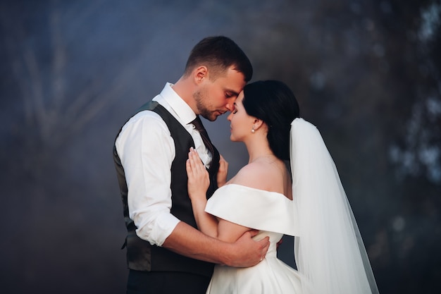 Bella coppia innamorata in abiti da sposa posa per la fotocamera