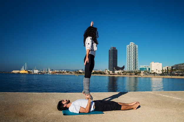 Beautiful couple practicing acro yoga in the morning outdoors near the sea. Balance and connection concept.