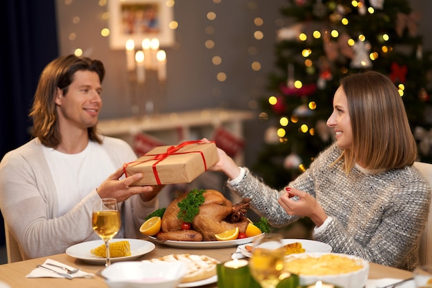 크리스마스 저녁 식사 동안 선물을 공유하는 아름다운 커플