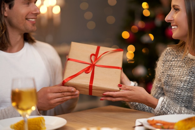 Beautiful couple sharing presents during Christmas dinner