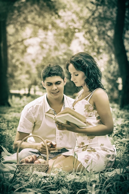 Photo beautiful couple sitting in the grass reading a book