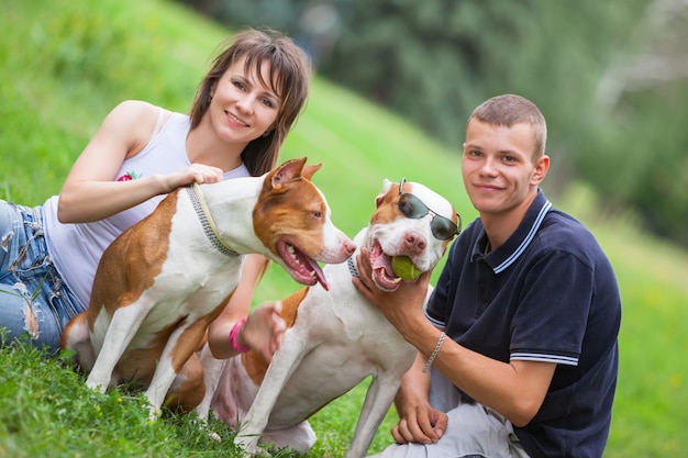 Beautiful couple sitting on grass with dogs 