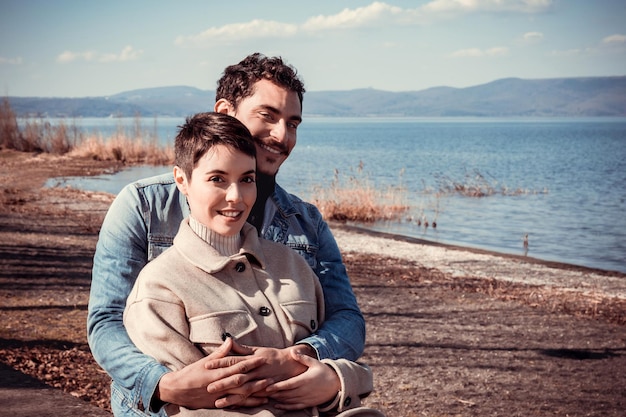 Beautiful couple sitting on the shore of lake bracciano in italy