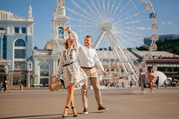 Beautiful couple smiling and posing near ferris wheel