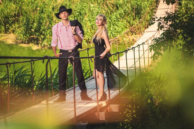 Beautiful couple standing on long wooden bridge in forest