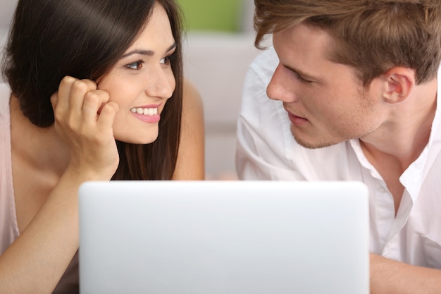 Beautiful couple surfing internet on laptop at home