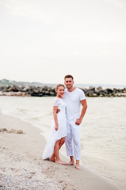 Beautiful couple in white clothes walking on the sea