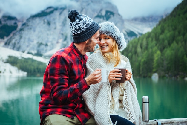 Beautiful couple of young adults visiting an alpine lake at Braies Italy