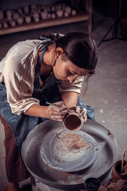 Bellissimo maestro artigiano lavora con l'argilla su un tornio da vasaio