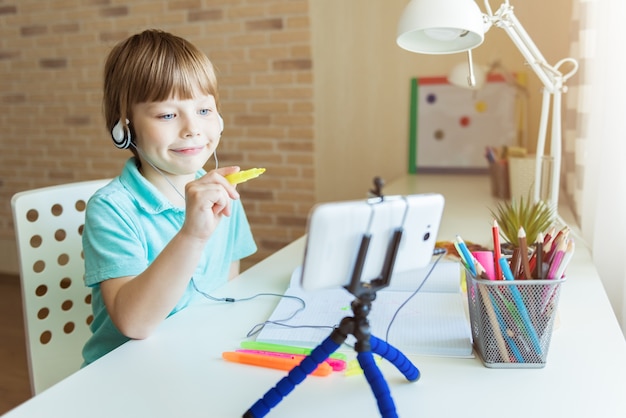 Beautiful creative boy is following online drawing lesson