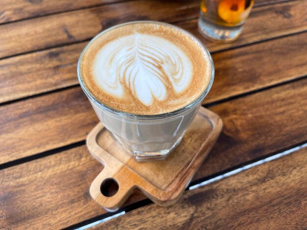 Beautiful cup of cappuccino coffee with latte art in the wooden space background